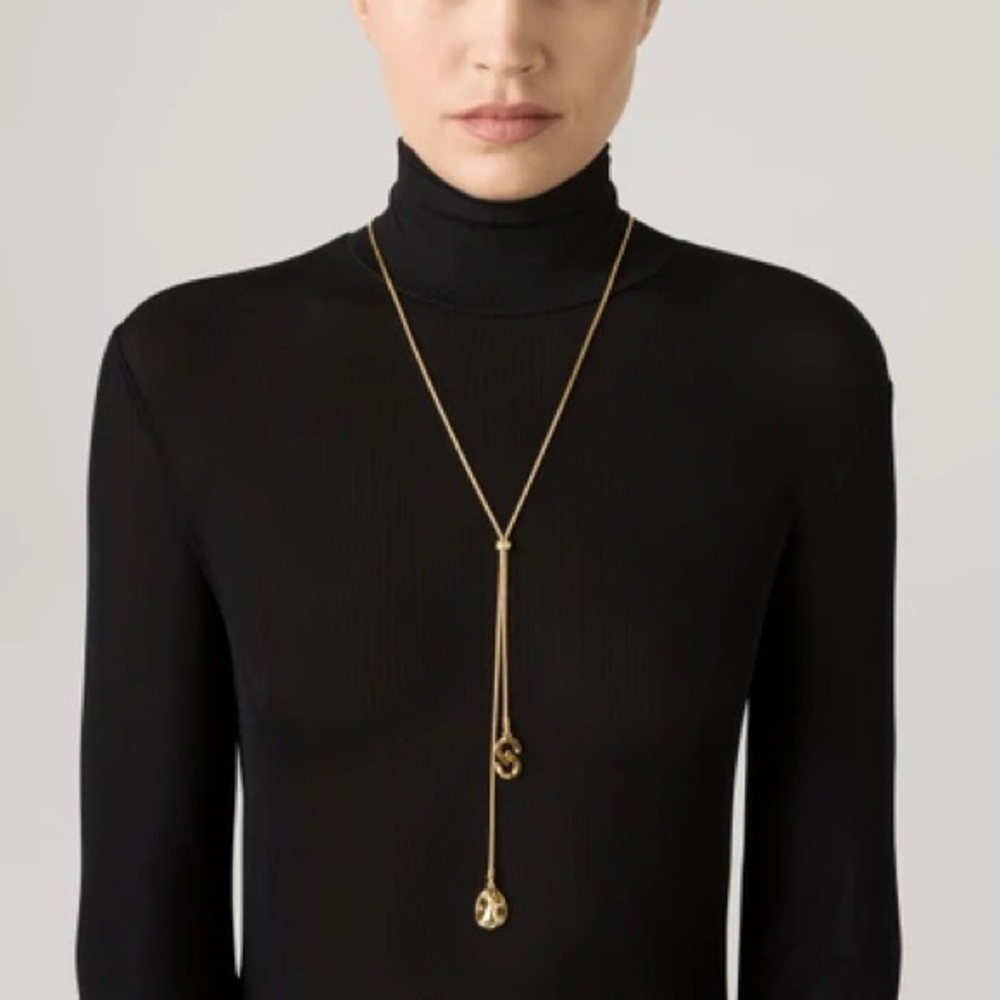 Effortlessly chic,long drop necklace features a gold St. John logo & disc